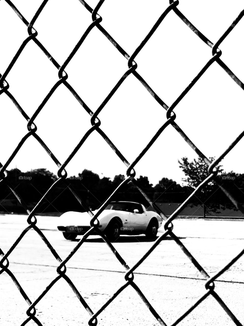 Corvette through a chain link fence. 