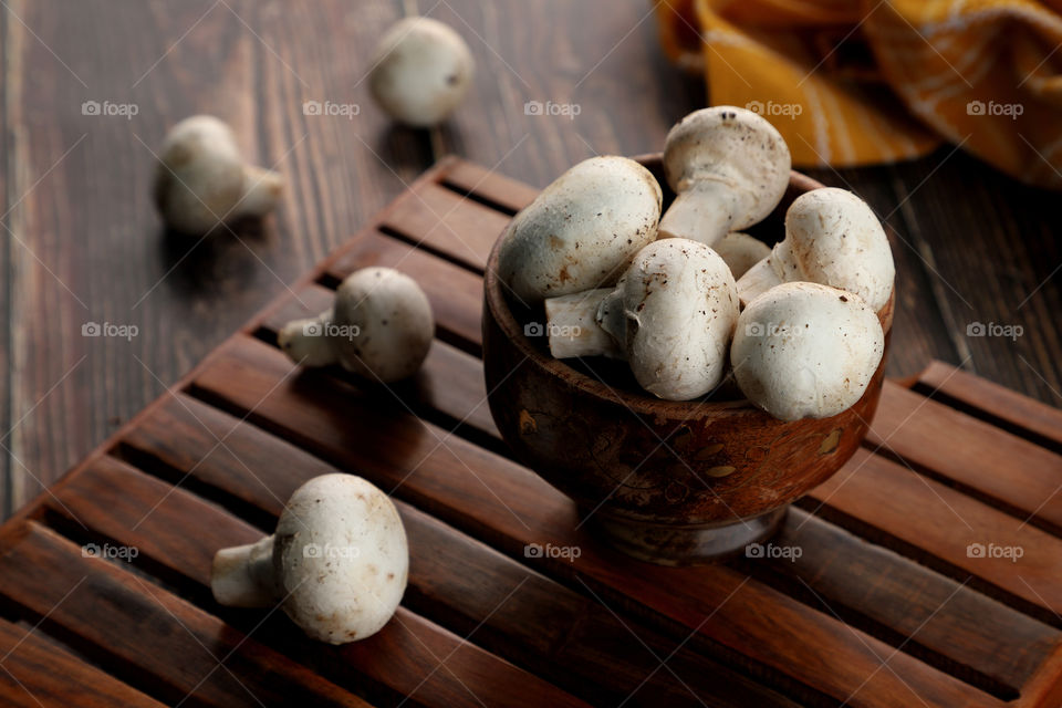 fresh organic button mushrooms in a wooden bowl