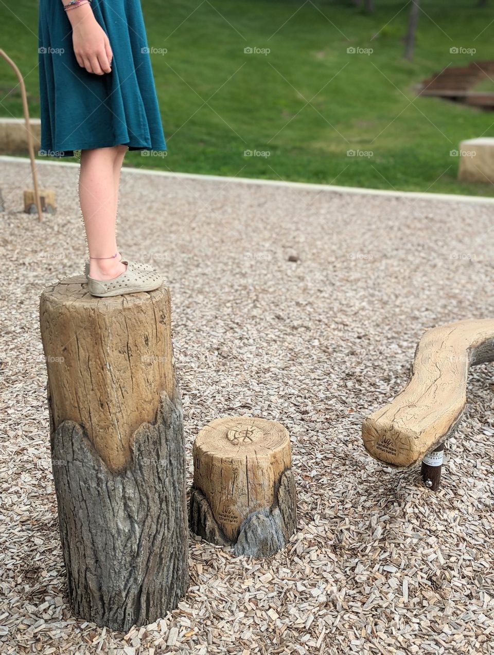 girl at playground standing on wood stepping stones playing the ground is lava wood stumps