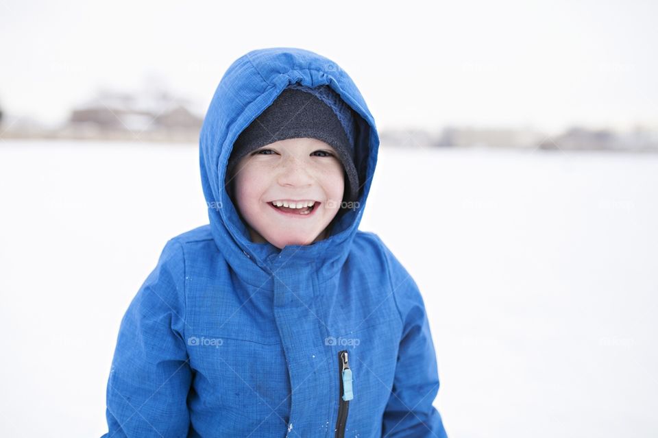 Boy smiling while sledding down a hill in winter 