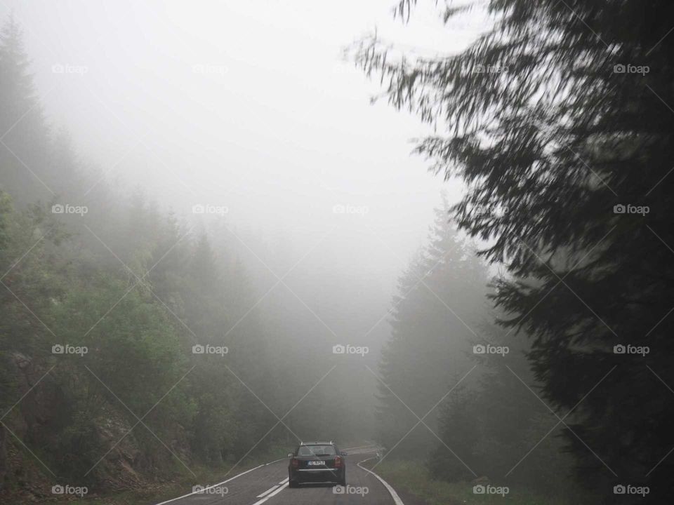 Dramatic lightning in the mountains with a car driving up the street during the dusty, foggy environment.