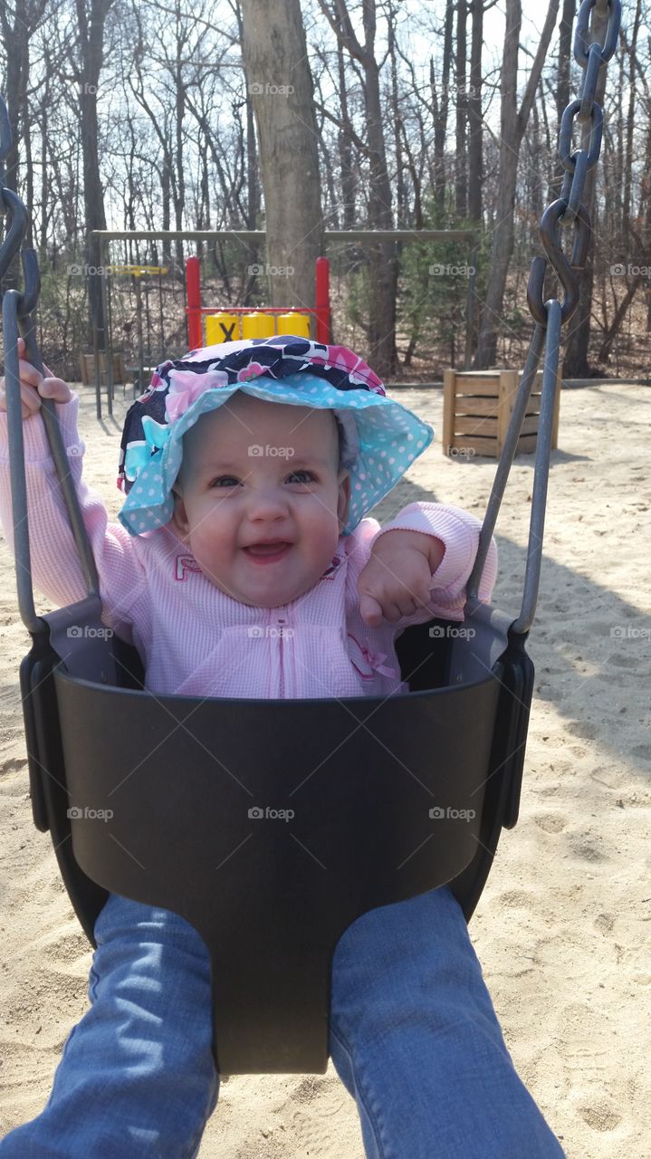 Happy baby in a swing at a park