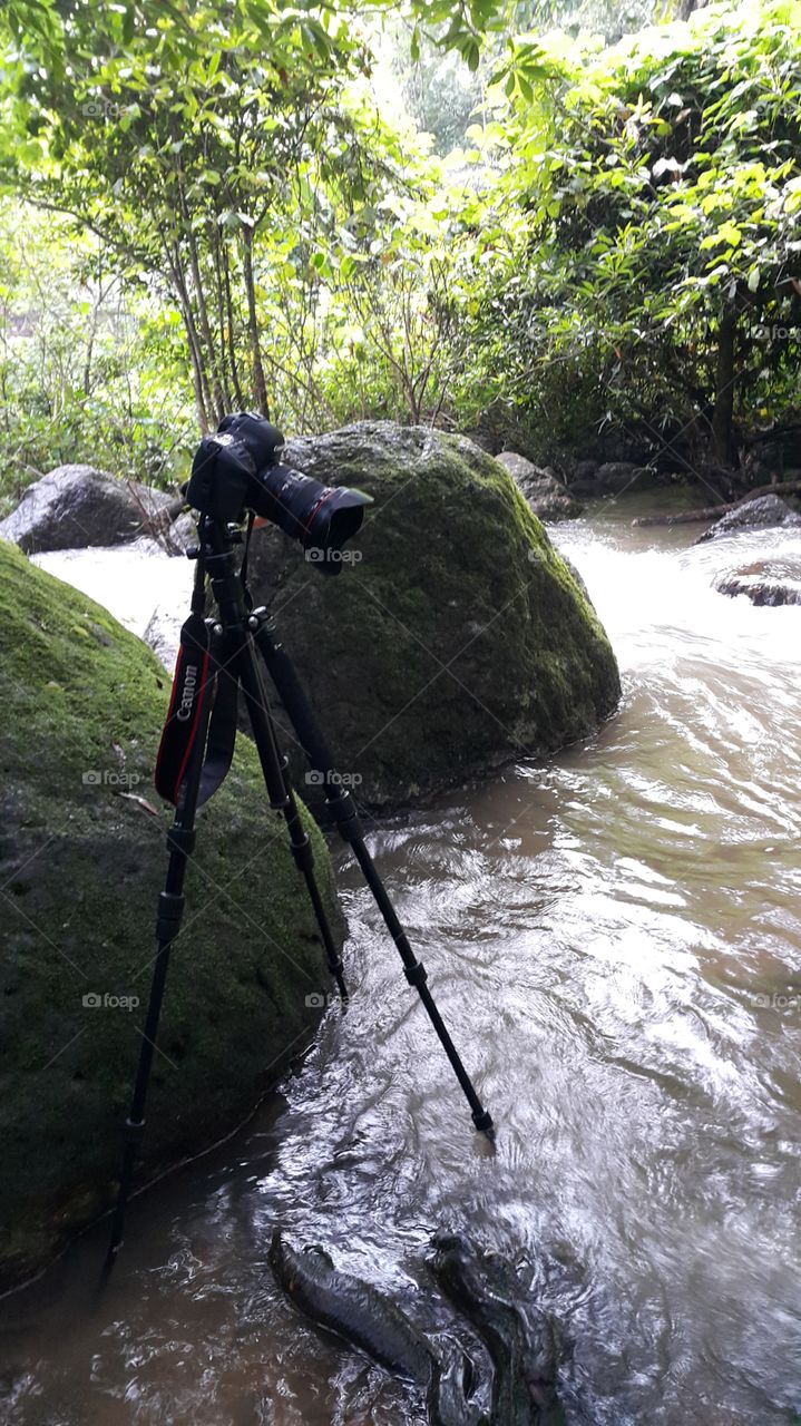 photography equipement set up for long exposure camera and tripod on location by the river in the forest