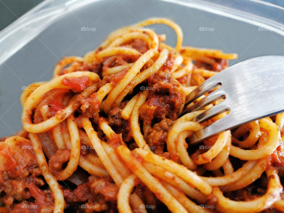 Spaghetti bolognese with fork in a plastic box.