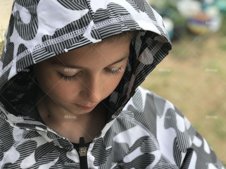 Little boy in a raincoat looking down