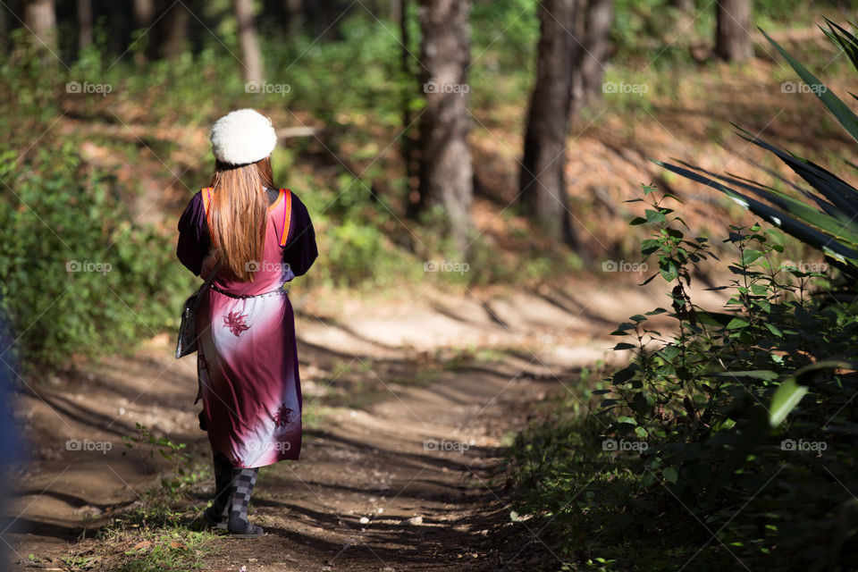 Rear view of woman walking in forest trail