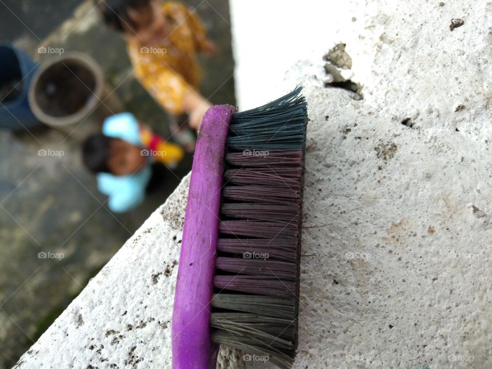 purple dirty toothbrush head with children playing in the background