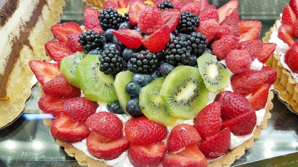 Delicious and beautiful fruit pie with blackberries, blueberries, kiwis, raspberries, strawberries and cream.