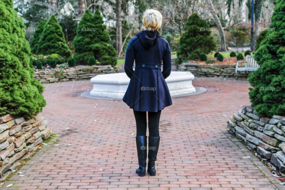 Here is a girl on a path in the garden. She can go multiple ways but is not choosing what to do. 