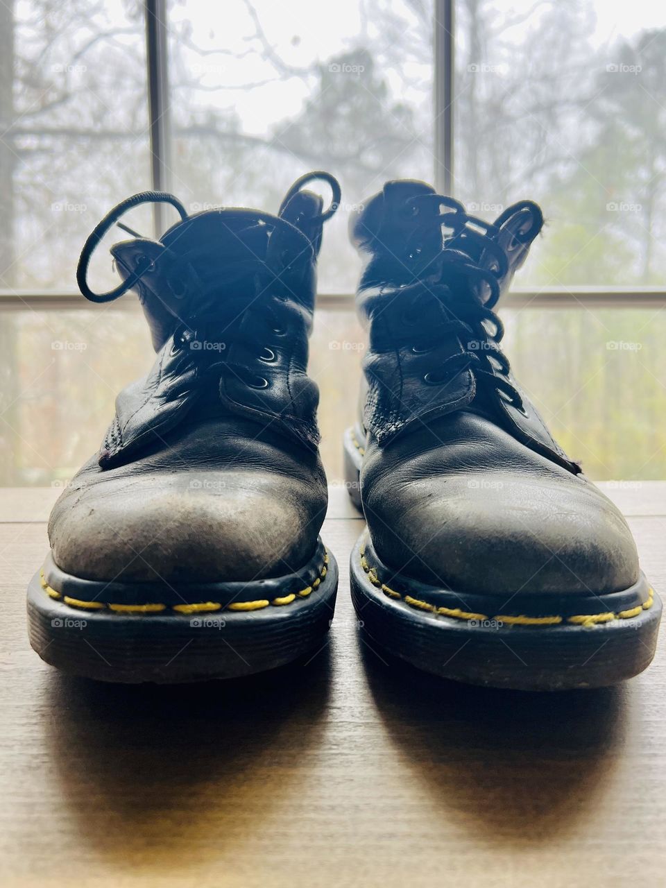 Closeup pair of worn classic Doc Marten boots backlit by window