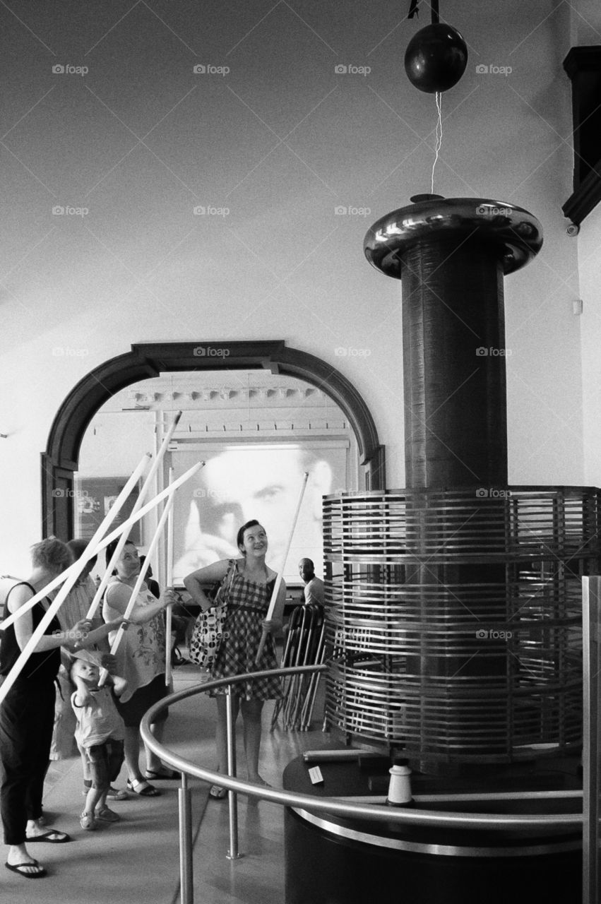 Women with tube light standing near electrical machine