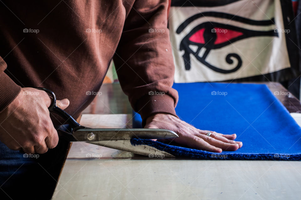 Tailor cutting textile and taking measurements