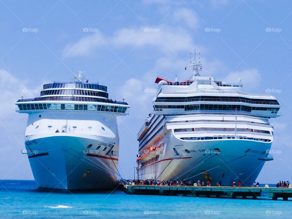 Cruise ships dock at port. Blue waters, white sands and people.