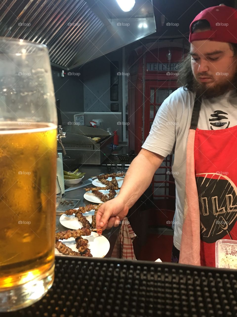 Barman making food behind a beer.