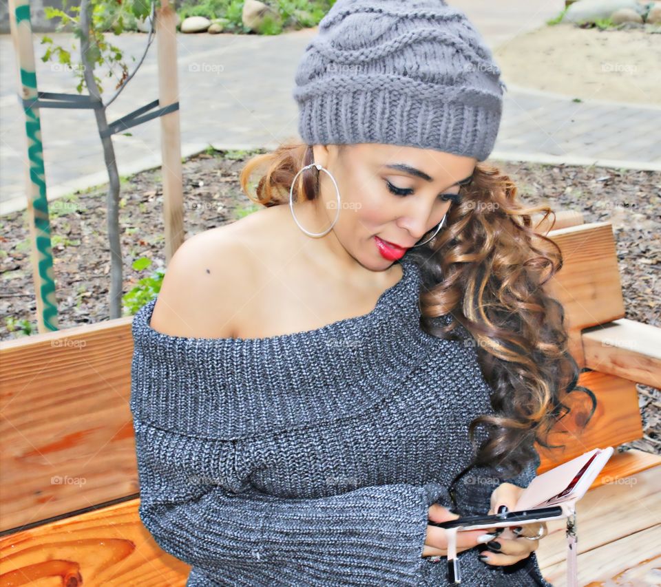 fashion lady sitting on a park bench on her iPhone outdoors in the park