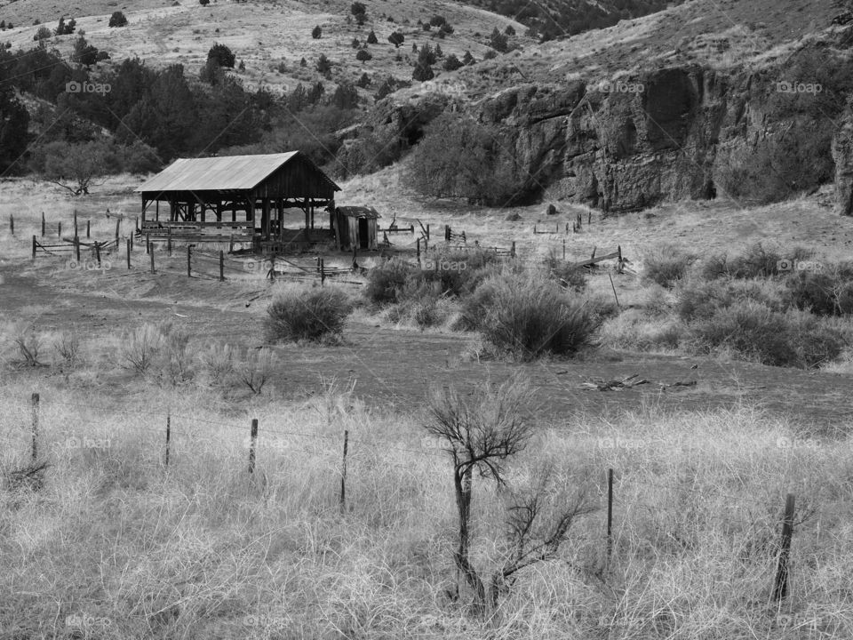 A hay storage building at the base of a cliff in rugged Eastern Oregon ranch land. 