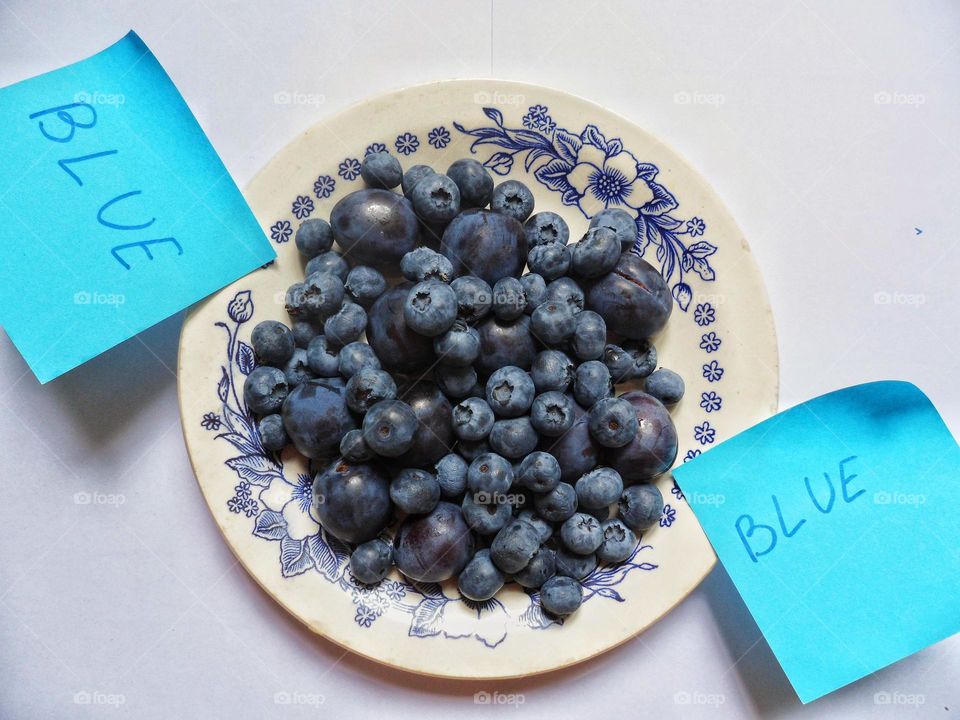 plums and blueberries lie in a plate