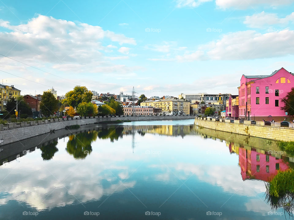 Beautiful Cityscape above the river with symmetrical reflection of cloudy sky in water