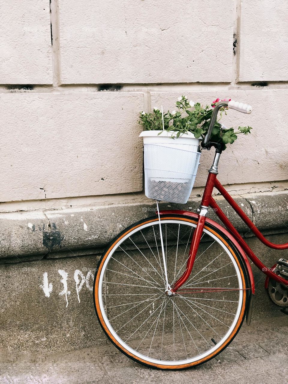 One lonely red bicycle with flowers on the street, nobody 