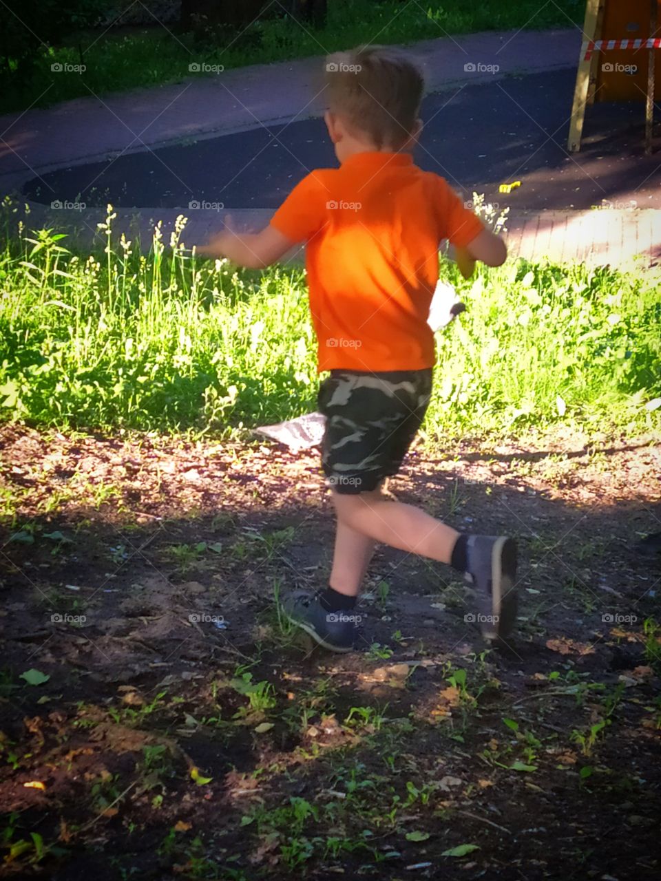 Summer day in the park.  Boy runs after pigeons