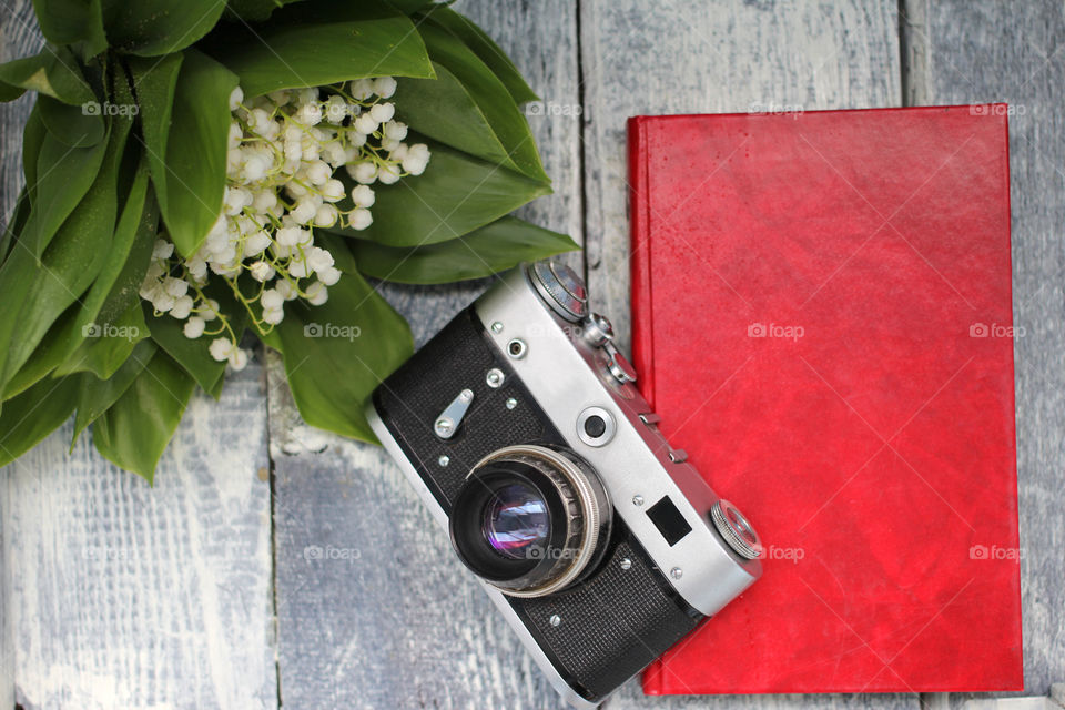 A bouquet of lilies of the valley, a camera and a book