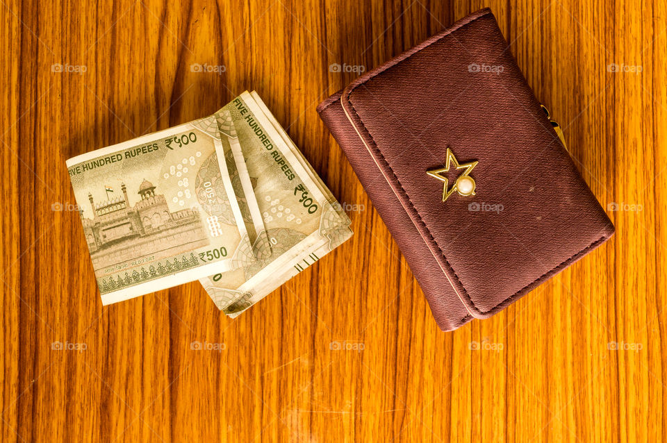 Indian five hundred (500) rupee cash note in brown color wallet leather purse on a wooden table. Business finance economy concept. High angel view with copy space room for text on front side of image