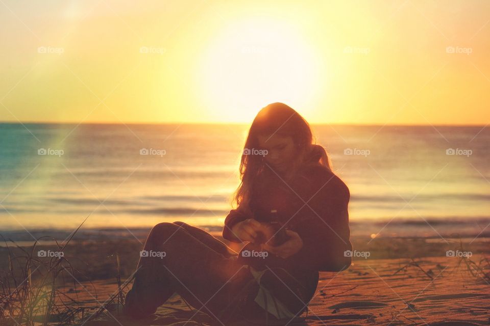 Woman capturing photo at beach during sunset