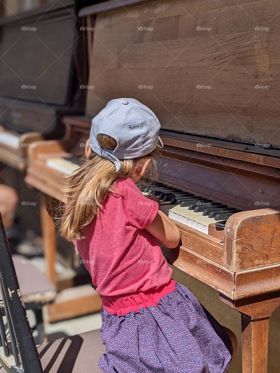 kid with cap playing the piano in the street