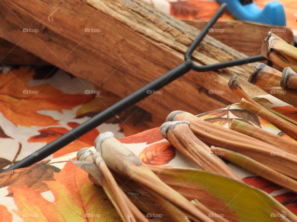 Autumn fall decor and cloth with logs and fire grate closeup with orange drawings of leaves, logs and dry palm leaves branches on a step.