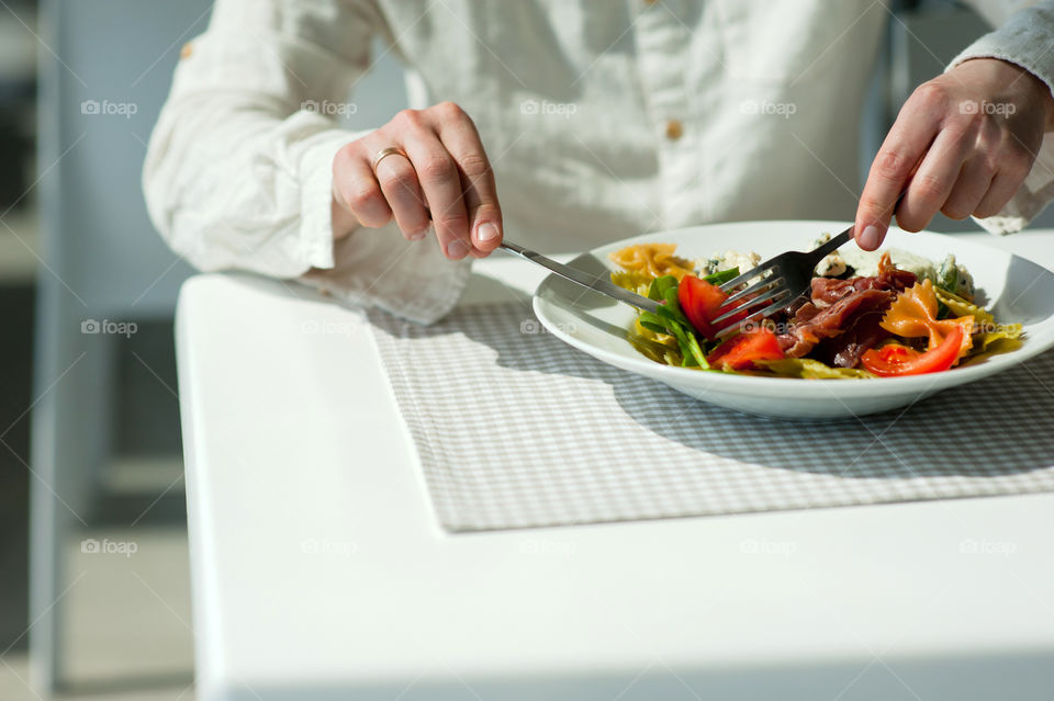 close-up of a young man eating a salad in a light kitchen