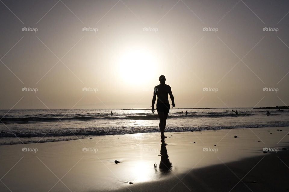 silhouette of man walking at sunset on the beach