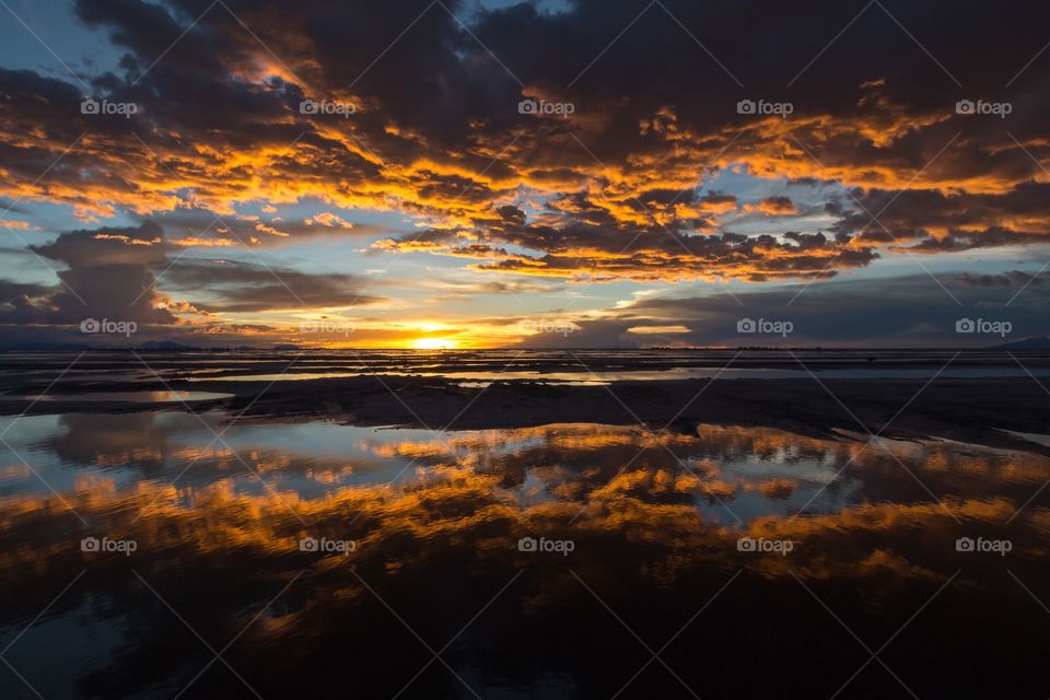 Sunset in Yuni salt flat. Dramatic sunset in Yuni salt flat in Bolivia. Reflection of colorful sky from water