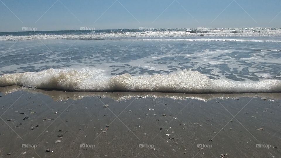 ocean waves on shore with blue sky