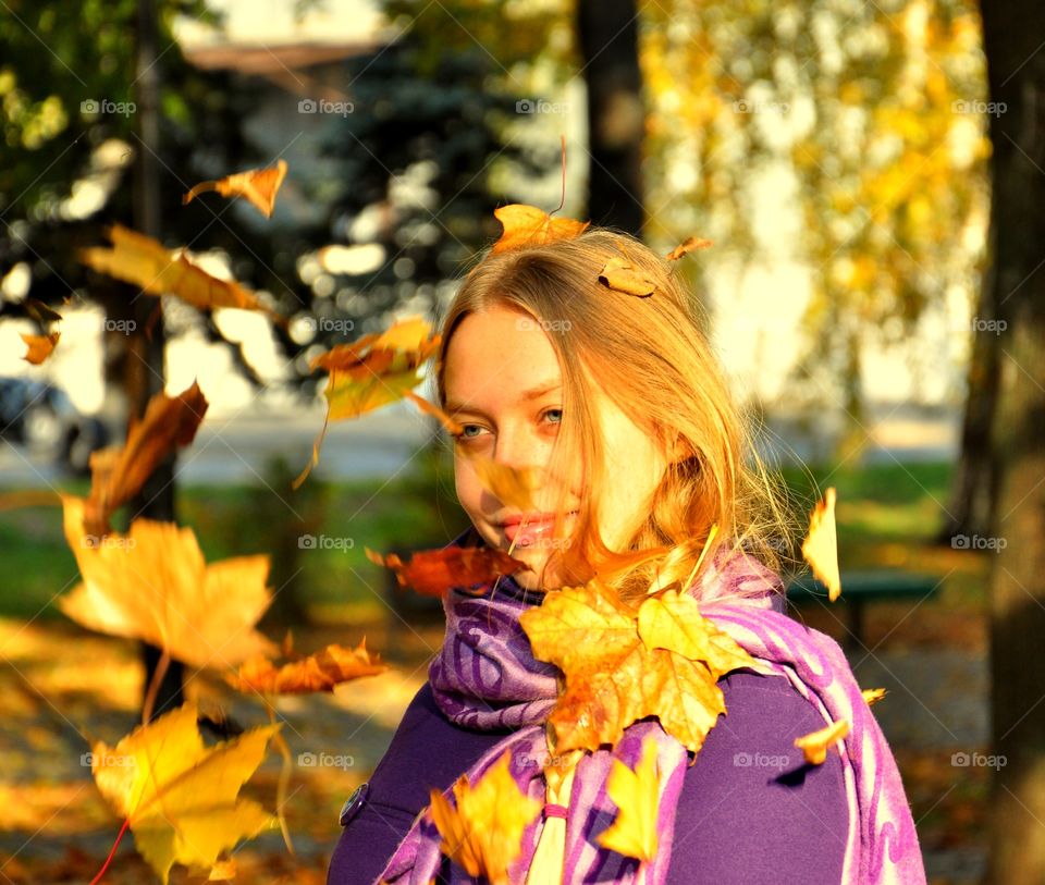 Close-up of a young woman with maple leaves during autumn