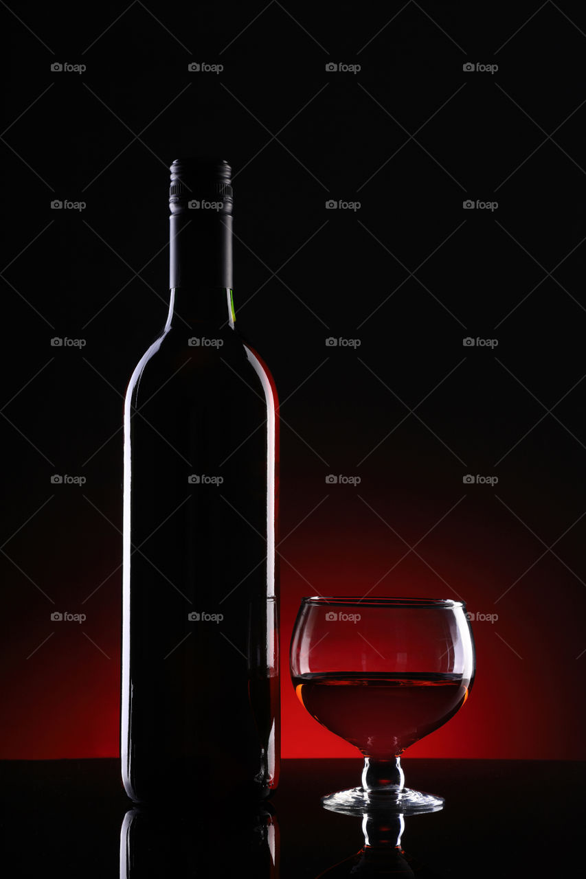 Red wine bottle and glass on dark background