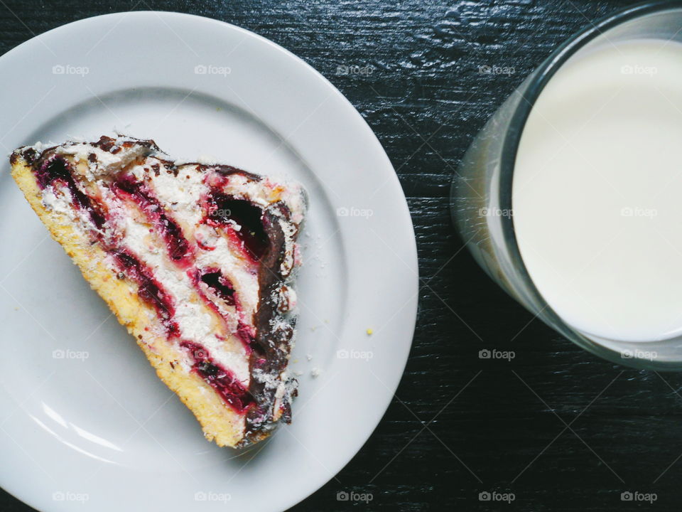 a cake with cherries and chocolate, and a cup of milk