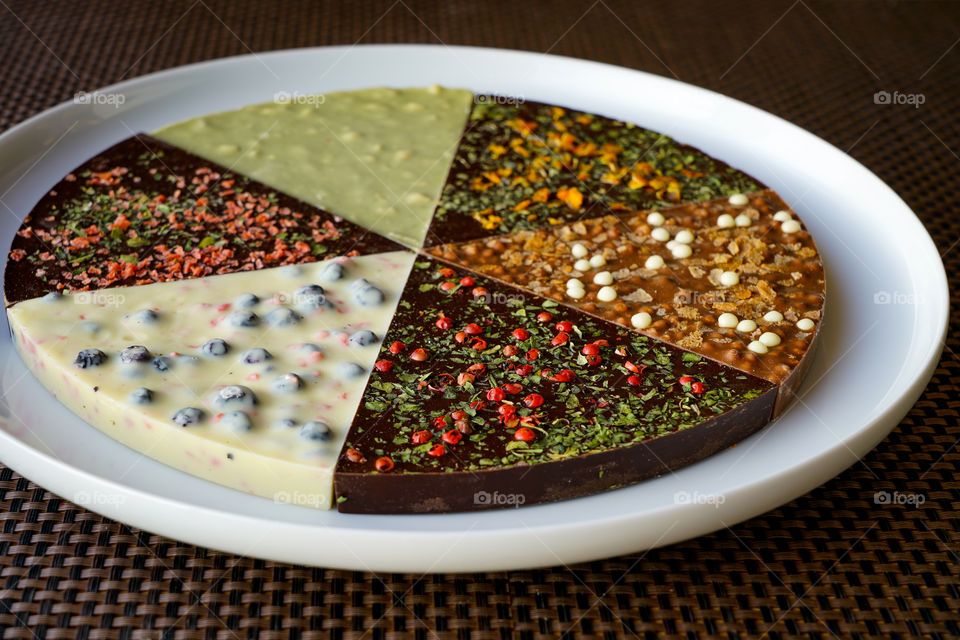 hand made chocolate pizza, assorted white, milk and dark chocolate with a six different flavours on a white plate