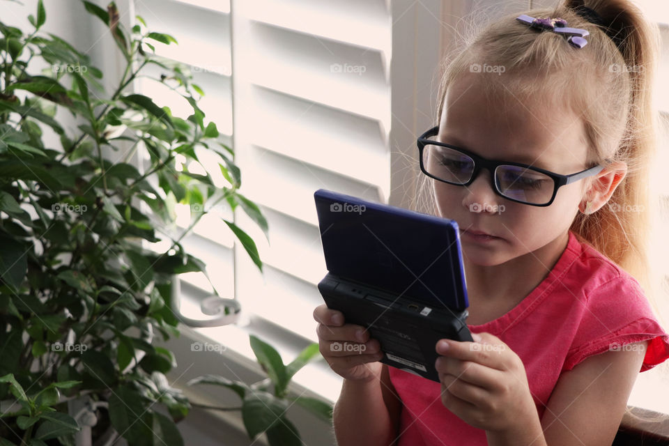 Child playing video games on a Nintendo DS Lite