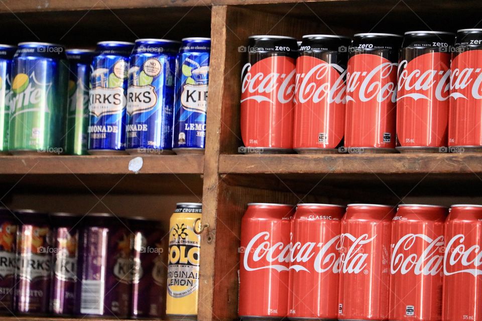 Modern canned soda beverages aligned on old fashion wood shelf, including Coca Cola 