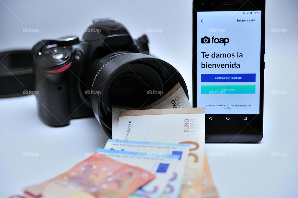An Smartphone showing Foap welcome page next to a camera with a lot of money in euros coming out of the lens.