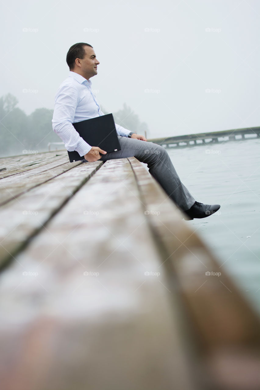 Man on lake dock with laptop