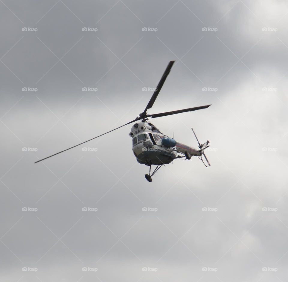 The helicopter is flying against the blue sky.