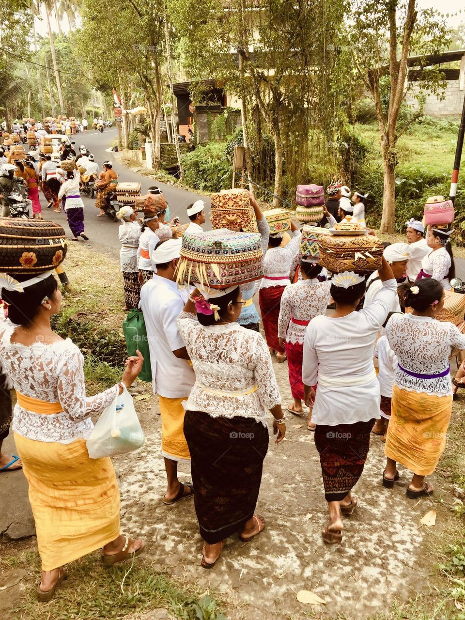 Group of ethnic Balinese people participate in a religious celebration wearing typical traditional clothes and carrying tributes on their heads