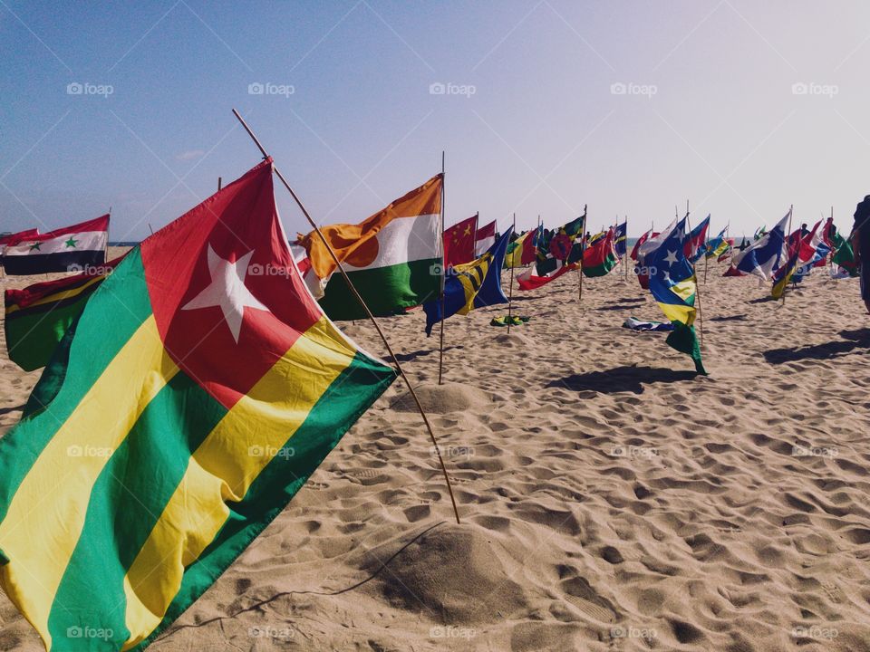 National flags waving in wind on beach. 