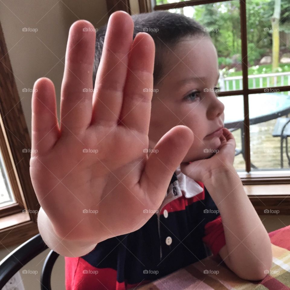 A boy sitting with stopping hand