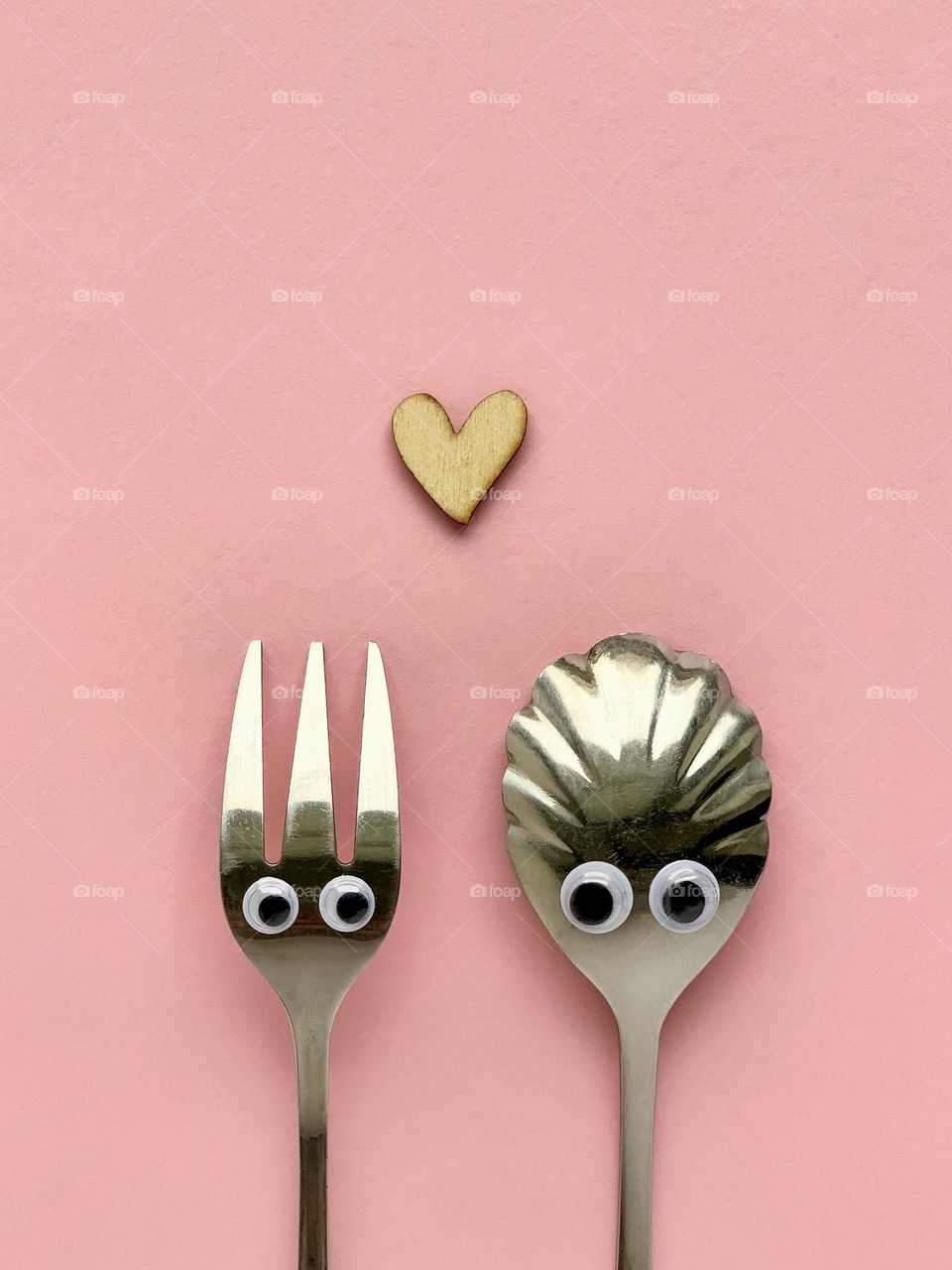 Fork and spoon with eyes in love, wooden heart, creative