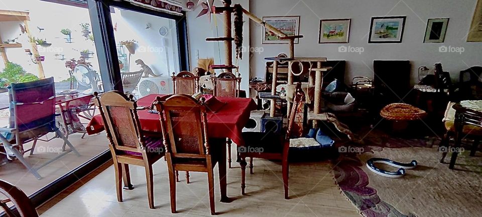 This is another section of the large L shaped living room of the house in „Bavaria“ w marble floors and a 20 foot long glass front with a sliding door leading to the garden. Antique furniture dominates the design here, too. 2023. Hypnotic Productions