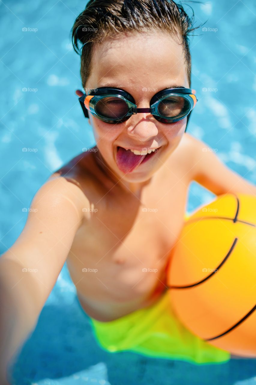 boy makes funny selfie in the pool