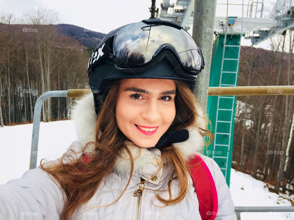 Portrait of young woman wearing Uvex ski glasses and Uvex helmet on the ski lift