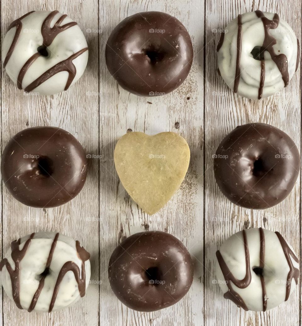 Ring donuts on a wooden background with a heart in the centre 